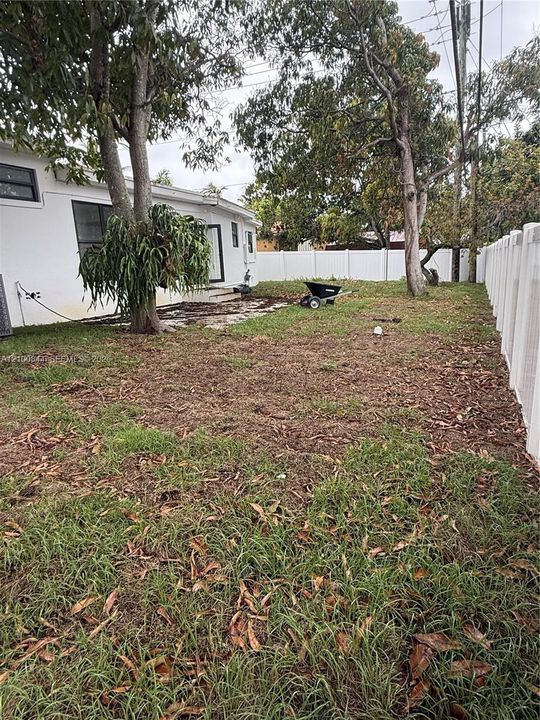 Backyard featuring a paved patio area, mature trees, and a perimeter vinyl privacy fence