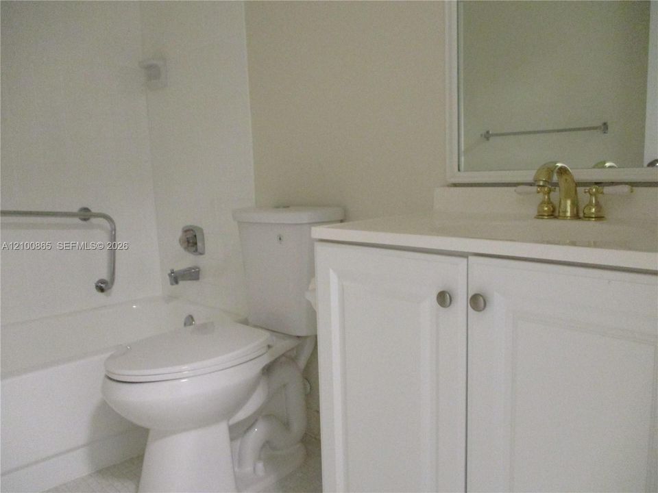 Guest bathroom with White vanity cabinet storage, brass-finish faucet, and integrated sink