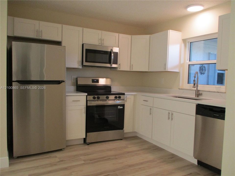 Kitchen featuring white shaker-style cabinetry, stainless steel appliances, granite countertops