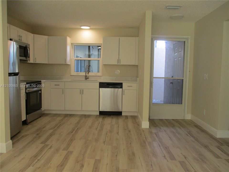 Kitchen featuring white cabinetry, stainless steel appliances, and an exterior door with a screen