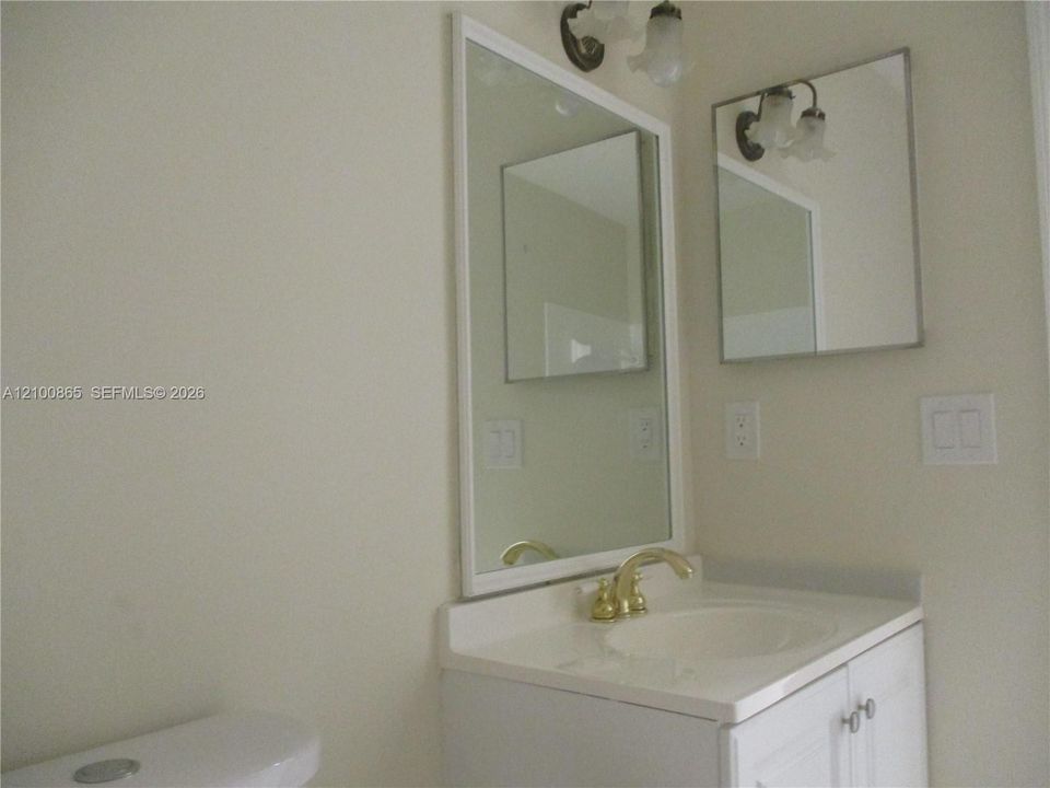 Guest bath with White vanity with a gold-finish faucet, an integrated sink