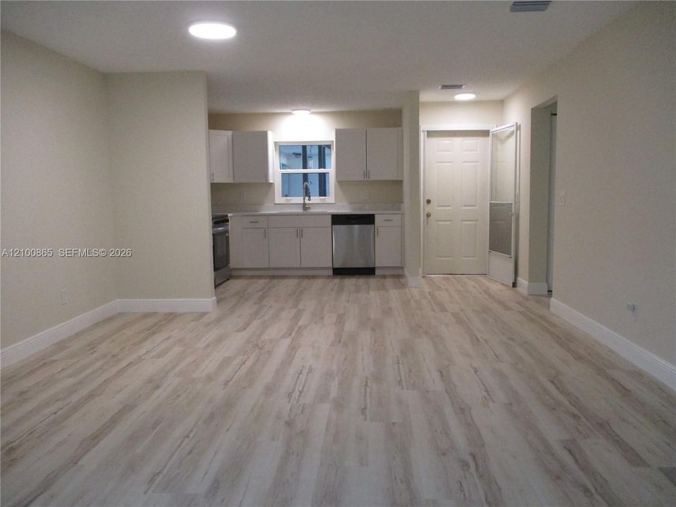Kitchen area featuring light-toned cabinetry, stainless steel appliances, and wood-finish flooring