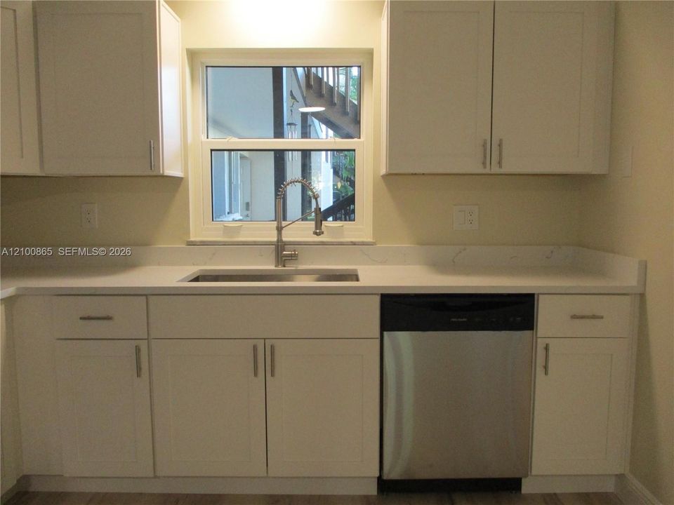 Kitchen featuring white shaker-style cabinetry, granite countertops, stainless steel undermount sink with a gooseneck faucet, and a stainless steel dishwasher