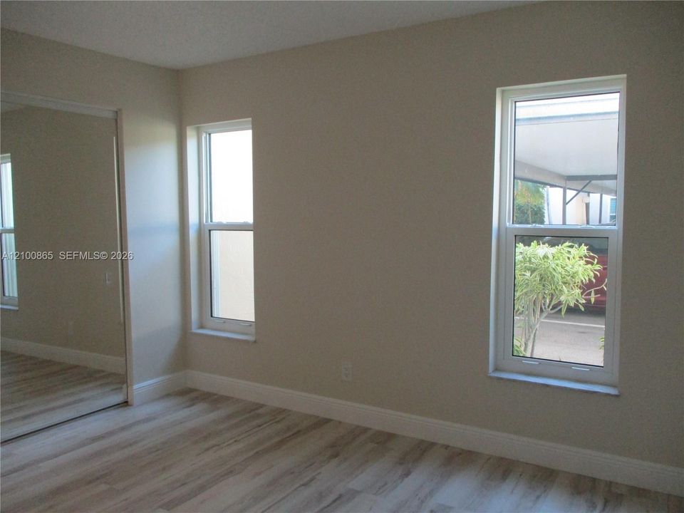 Guest Room featuring wood-finish flooring, dual windows, and a mirrored closet door