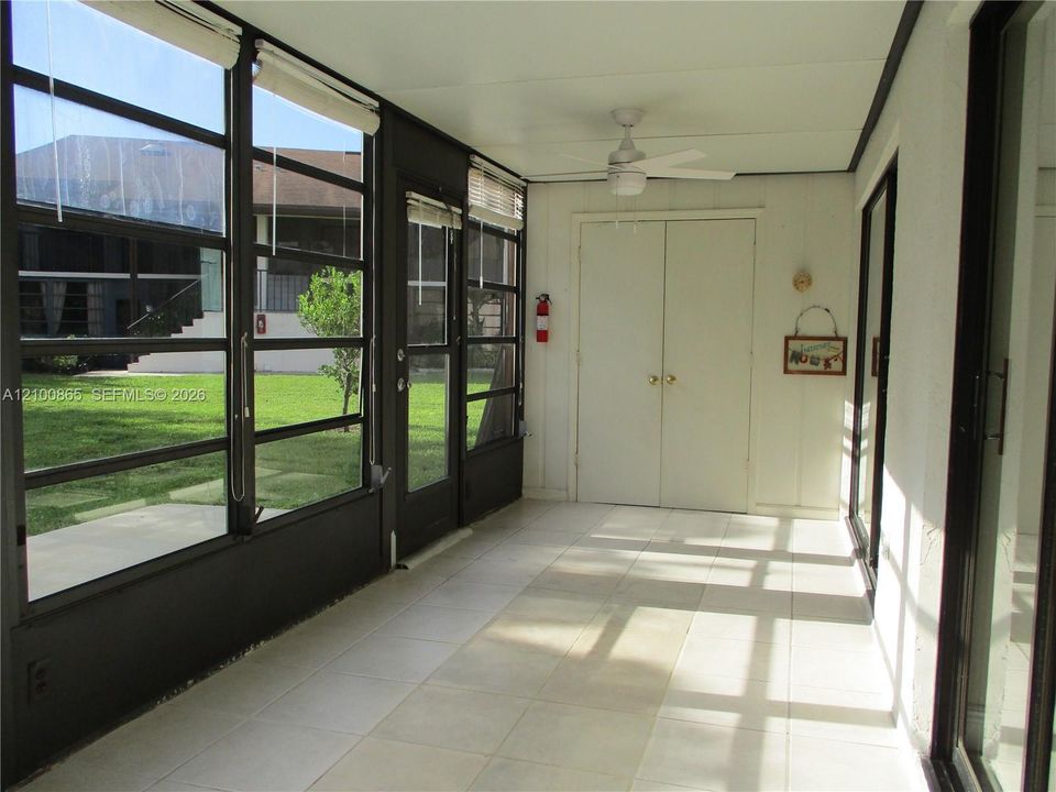 Enclosed patio featuring tile flooring, full-height windows, a ceiling fan, and double doors, storage area at end with washer & dryer