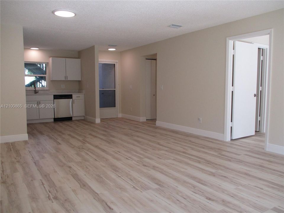 Maple LVP throughout, recessed lighting, white cabinetry, stainless steel dishwasher, and a lightwhite-colored countertop