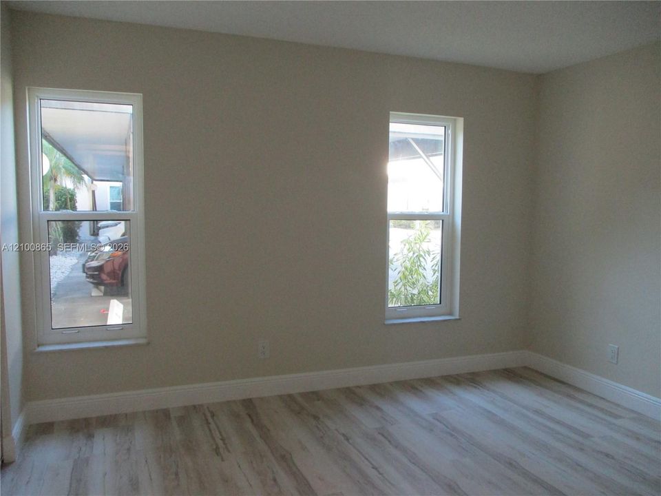 Guest room with Neutral-toned interior walls featuring dual double-hung windows and wood-finish flooring