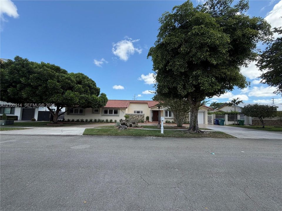 Exterior featuring a stucco facade with stone masonry accents, a tiled roof, a multi-car garage, and a concrete driveway