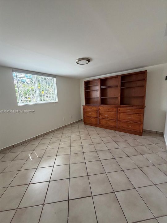 Kitchen featuring light-finish cabinetry with glass-panel upper doors, stone-surface countertops, stone-pattern backsplash, stainless steel dishwasher, and ceramic tile flooring