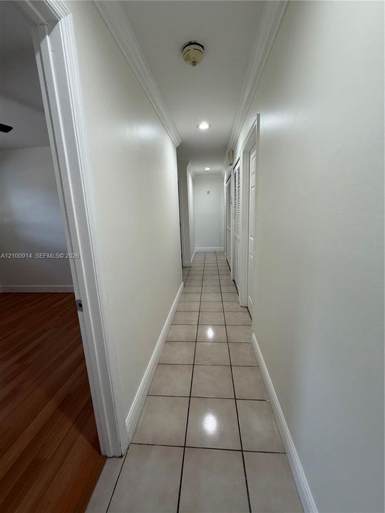 Neutral interior space featuring large-format ceramic tile flooring, horizontal window blinds, and a central semi-flush mount light fixture