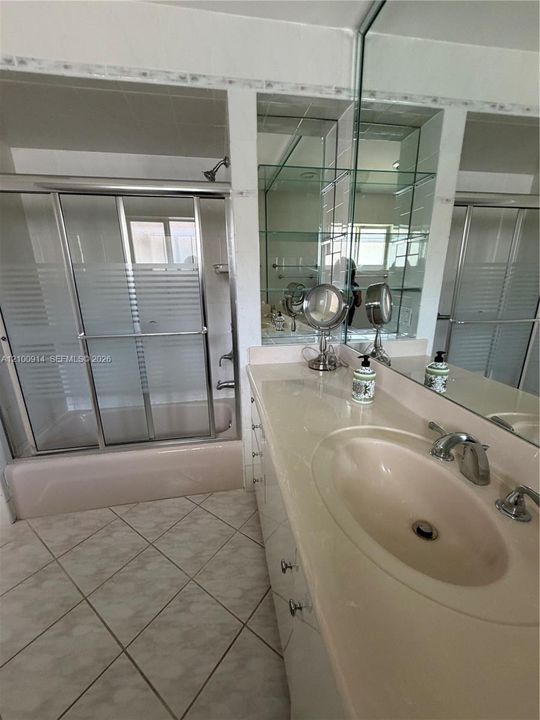 Built-in wooden cabinetry featuring open shelving and integrated drawers, ceramic tile flooring, and a window with security grating