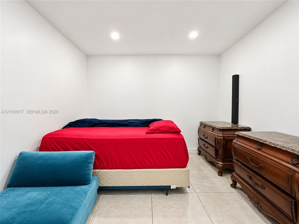 Recessed lighting illuminates the white walls and large format tile flooring