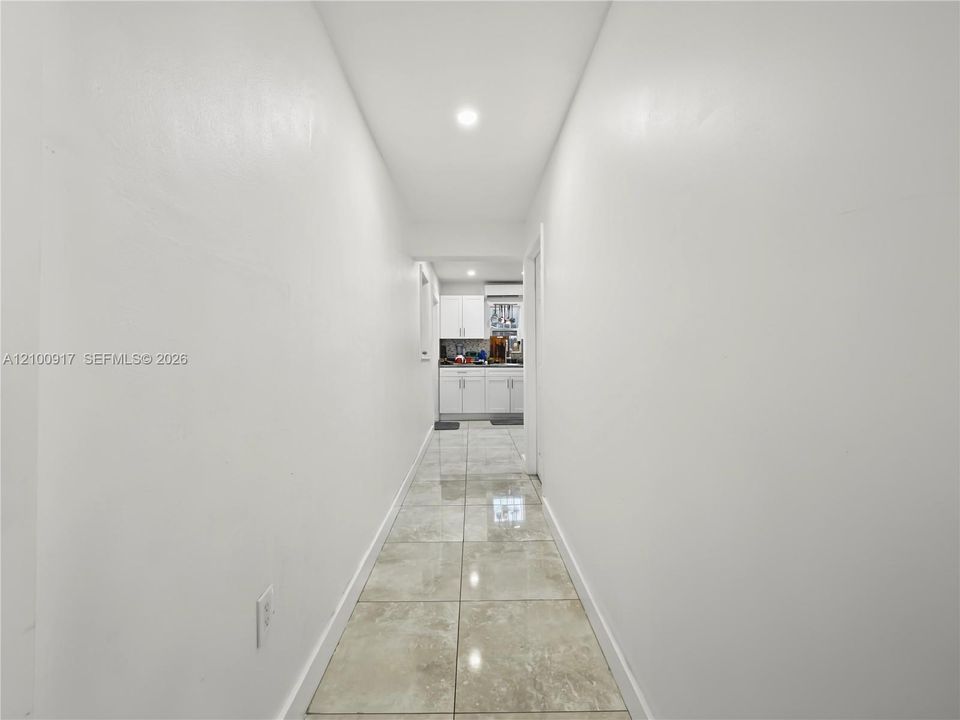 Recessed ceiling lighting illuminating a hallway with light-colored walls and tiled flooring
