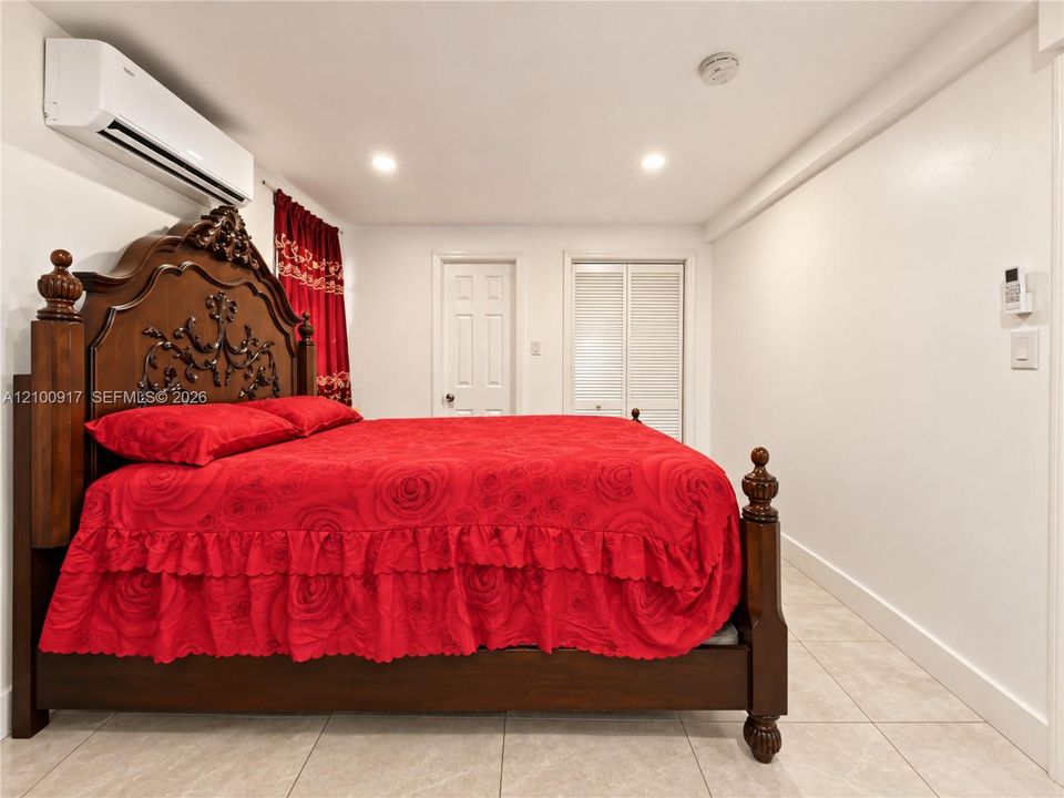 Tile flooring, recessed lighting, split air conditioning unit, white walls, and a built-in closet with louvered bifold doors