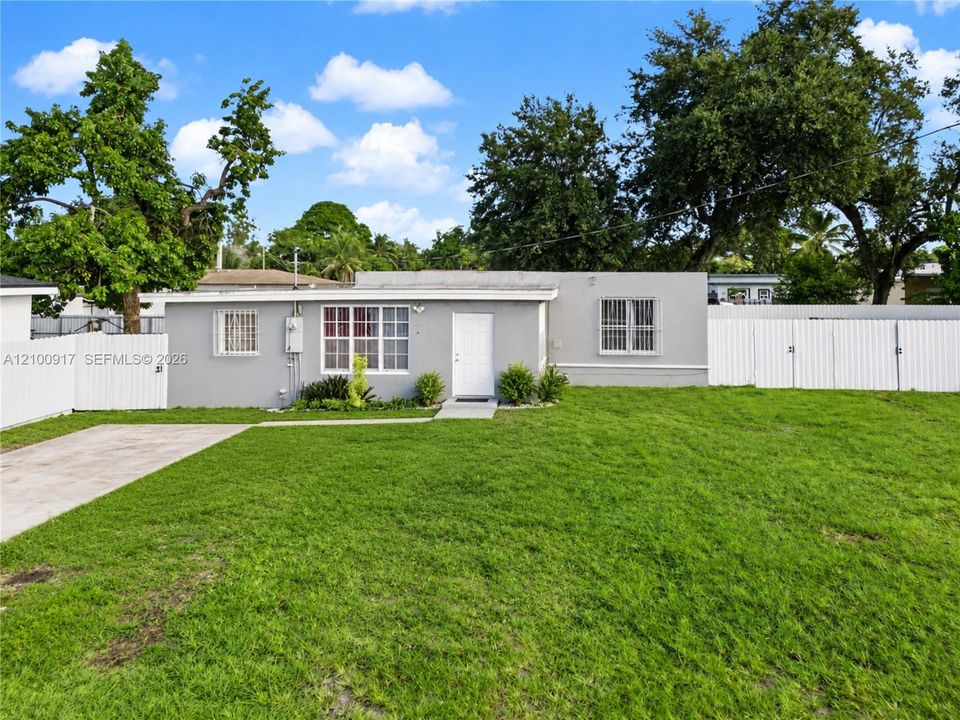 Single-story residence with a gray facade, white privacy fencing, and a concrete driveway