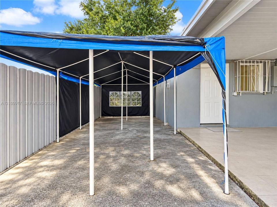 Covered entry area with concrete flooring, light gray exterior wall, and white entry door