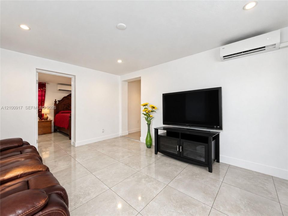 Recessed ceiling lighting, mini-split air conditioning unit, light-toned tile flooring, and white baseboards