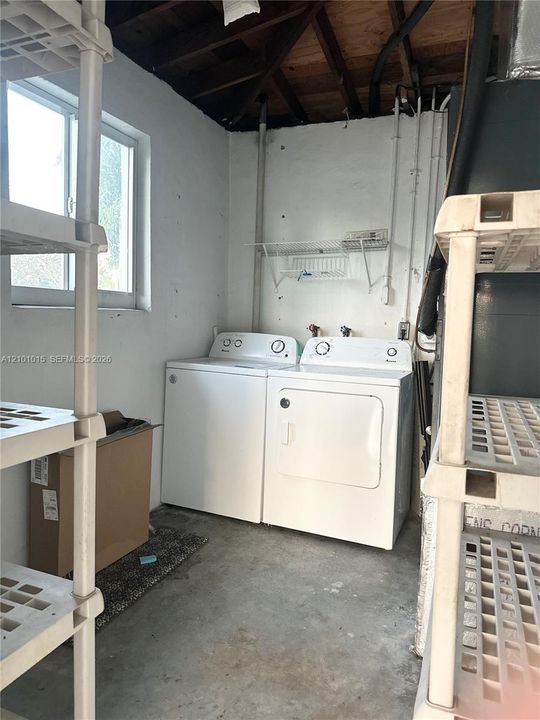 Laundry area featuring concrete flooring, a horizontal sliding window, and a wall-mounted wire storage rack