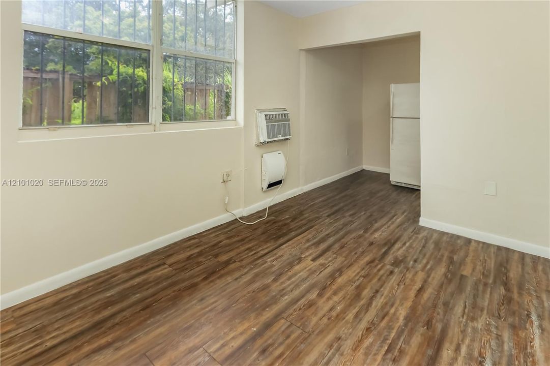 Room interior featuring wood-finish flooring, large multi-pane windows, and a wall-mounted cooling unit