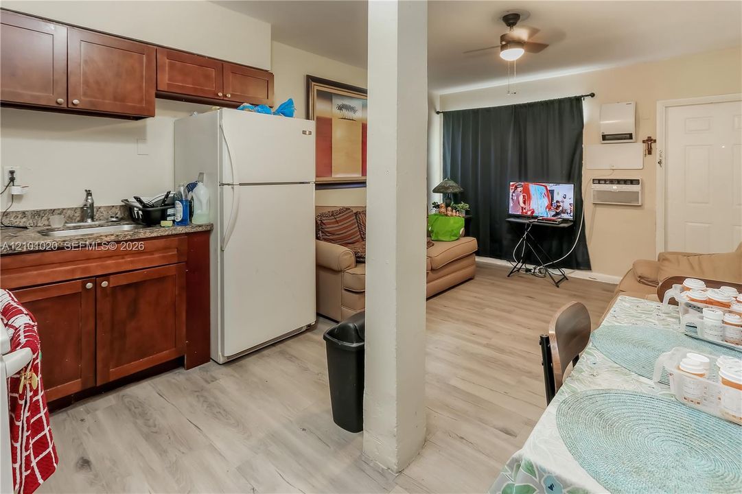 Kitchen featuring wood-finish cabinetry, stone-texture countertops, and stainless steel sink, complemented by wood-finish flooring and a ceiling-mounted light fixture with fan