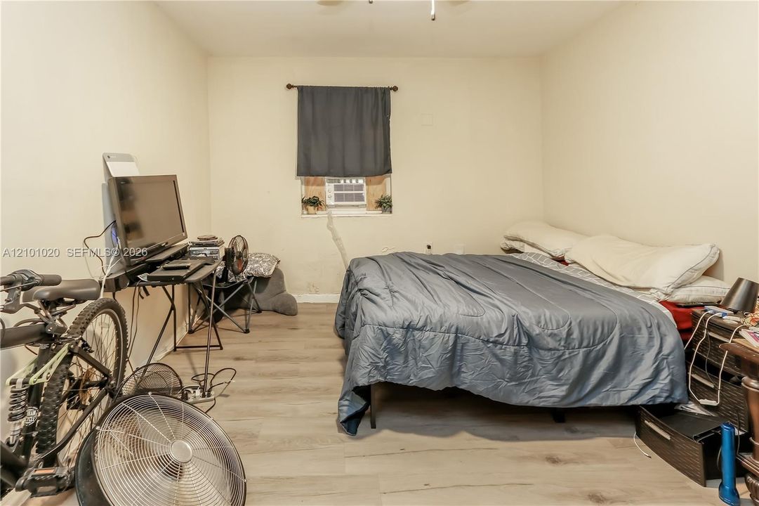 Neutral-toned walls and wood-finish flooring featuring a single-pane window with a mounted curtain rod