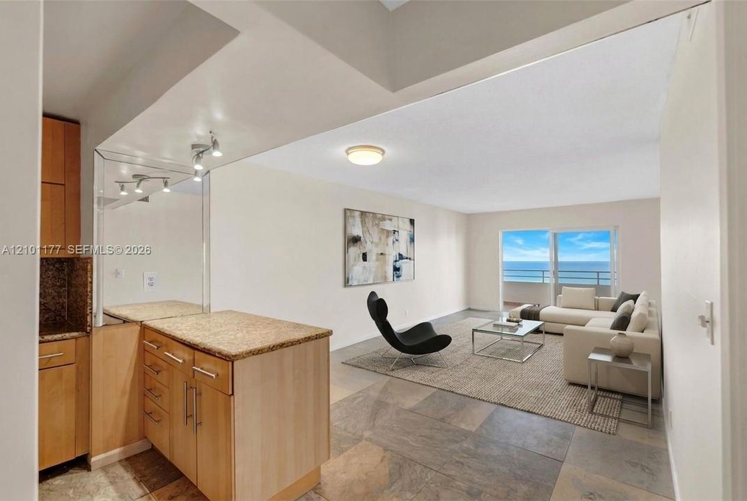 Natural stone tile flooring, custom wood-finish cabinetry, stone countertops, and a sliding glass door opening to an exterior balcony