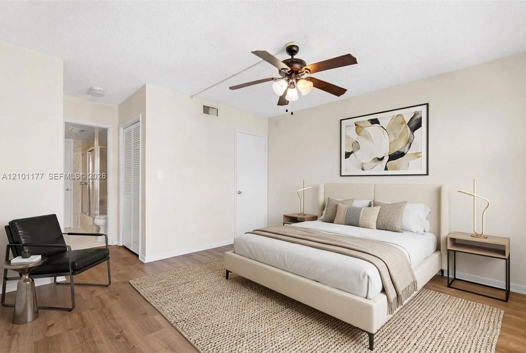Neutral interior featuring wood-finish flooring, a multi-blade ceiling fan with integrated lighting, and louvered closet doors