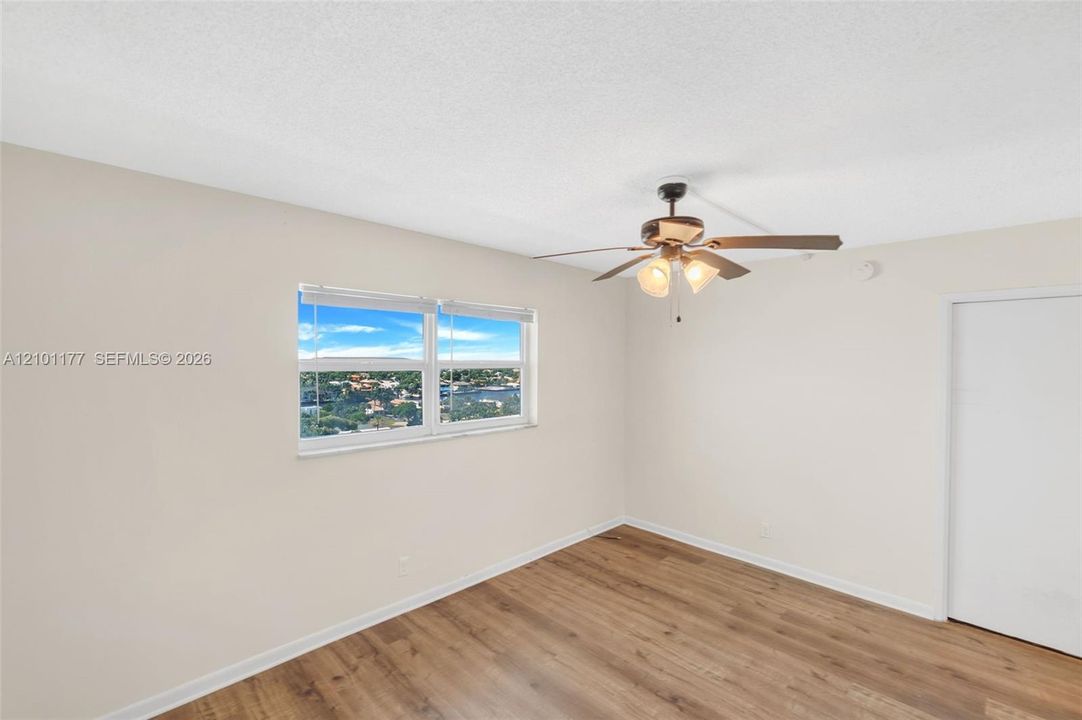 Interior space featuring wood-finish flooring, a ceiling fan with integrated lighting, and a window with exterior scenery