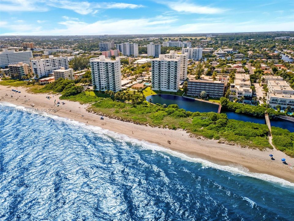 Aerial perspective of oceanfront property featuring sandy coastline, direct water access, and prominent high-rise architecture