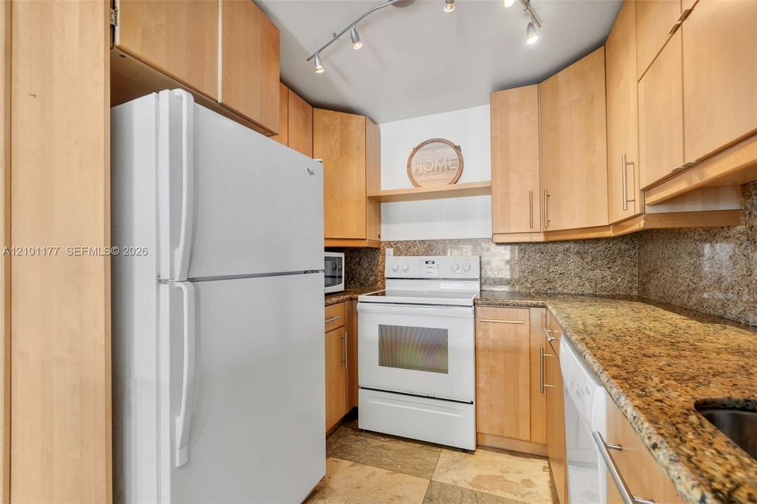 Kitchen featuring light-finish cabinetry, stone-texture countertops, stone-tile flooring, white appliances, and ceiling-mounted track lighting