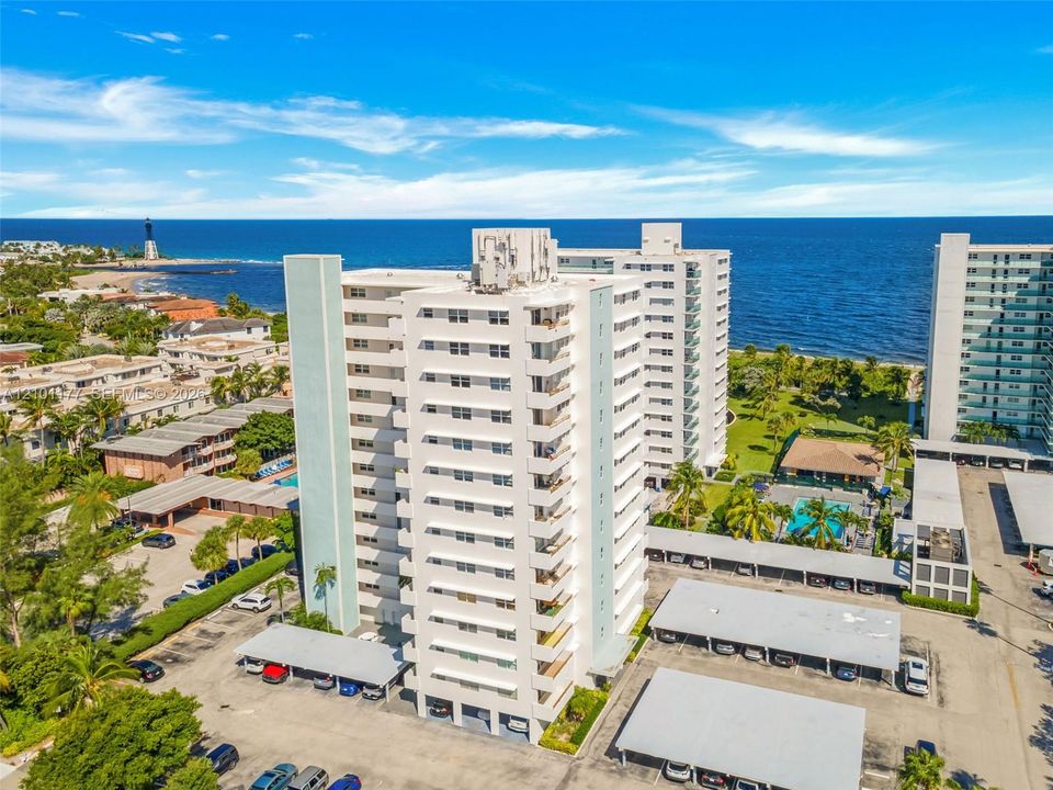 High-rise residential building featuring private balconies, expansive shoreline proximity, structured carport parking, and manicured grounds