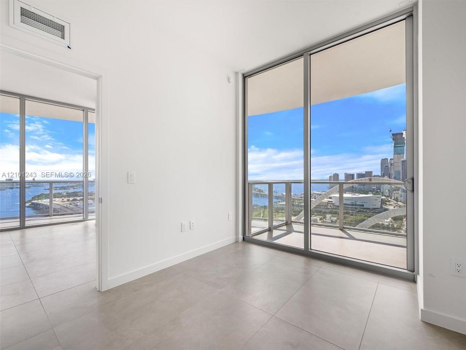 Floor-to-ceiling glass sliding doors, large-format tile flooring, and metal-framed balcony railings