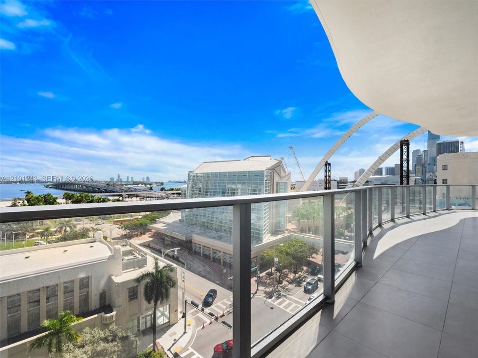 Covered balcony featuring large-format porcelain tile flooring and a glass panel railing