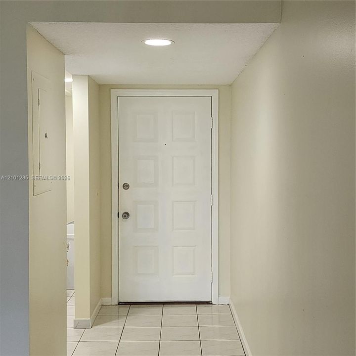 Entryway featuring a white eight-panel door, neutral tile flooring, and recessed ceiling lighting
