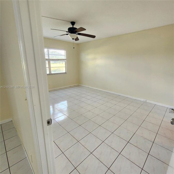 Interior space featuring neutral wall paint, large-format tile flooring, and a multi-blade ceiling fan with an integrated light fixture