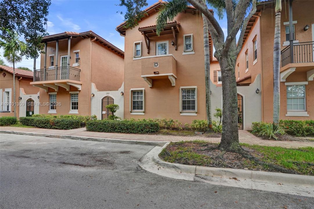 Mediterranean-inspired exterior featuring stucco facades, tile roofing, decorative balconies with wrought-iron railings, arched entryway gates, and multi-pane windows