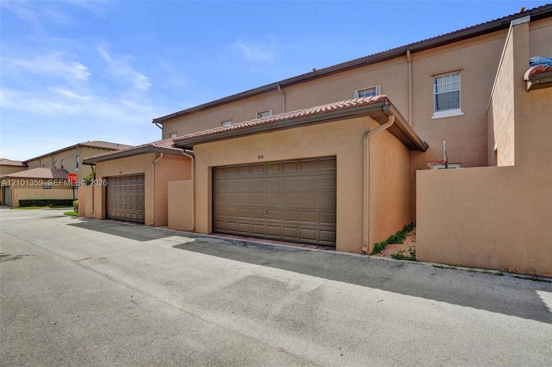 Stucco exterior featuring dual-bay garages with paneled sectional doors and tile roofing