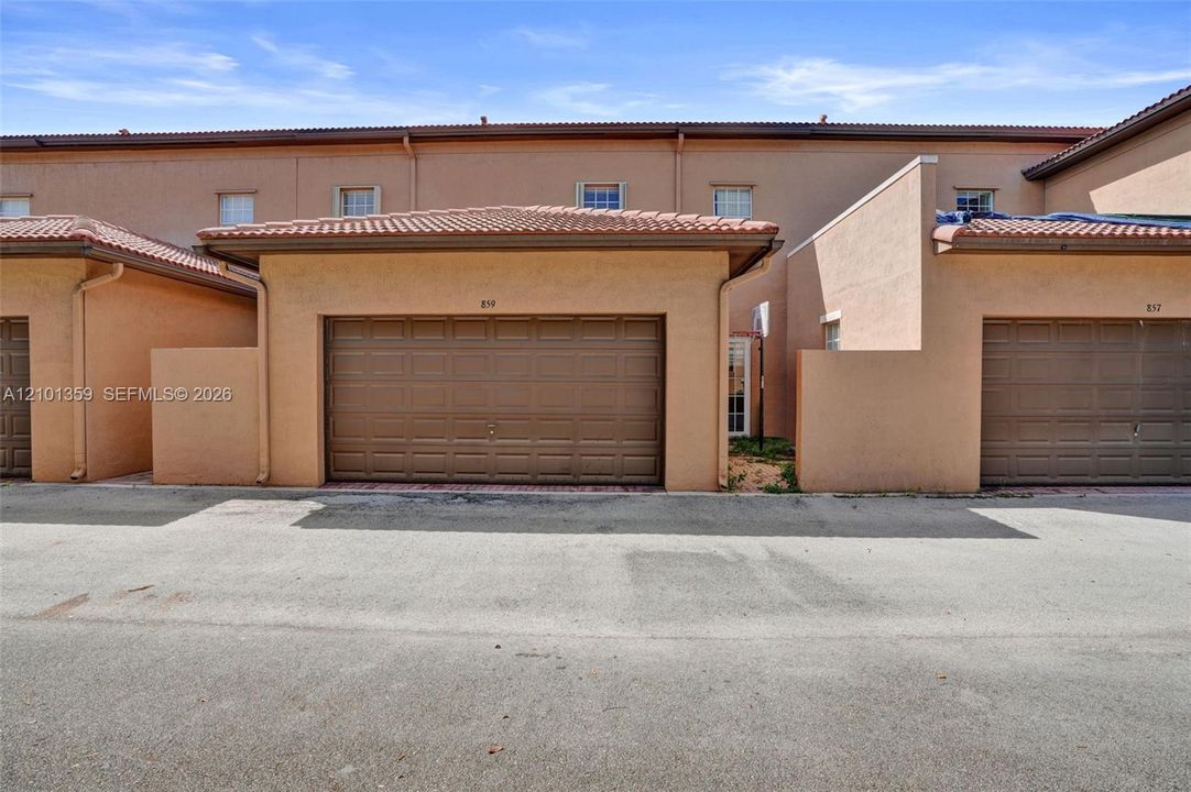 Stucco exterior with mission-style tile roofing and attached single-car garage featuring a paneled door