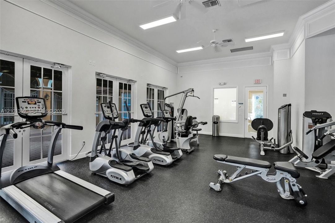 Fitness facility featuring high ceilings with crown molding, recessed lighting, rubberized flooring, and multiple glass-paned double doors