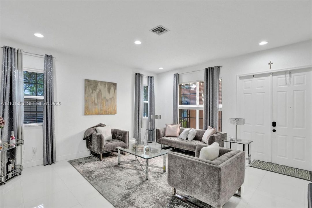 Living area featuring large-format tile flooring, recessed lighting, and double-entry doors