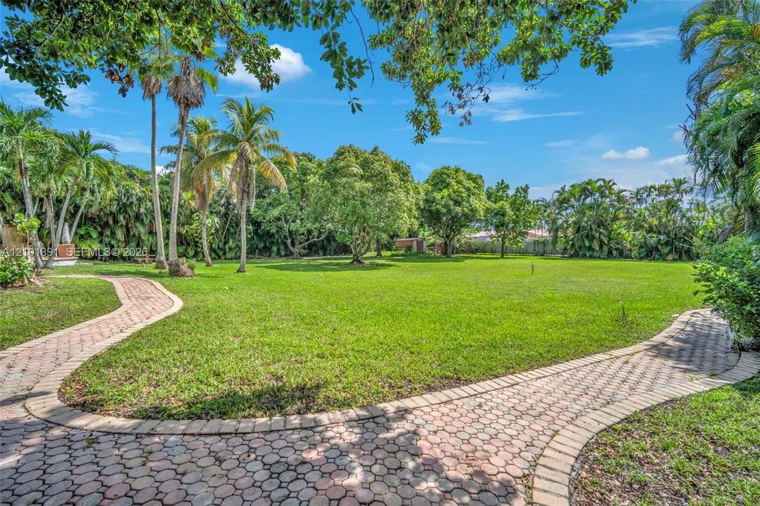 Expansive lawn area with mature trees and paved stone pathways