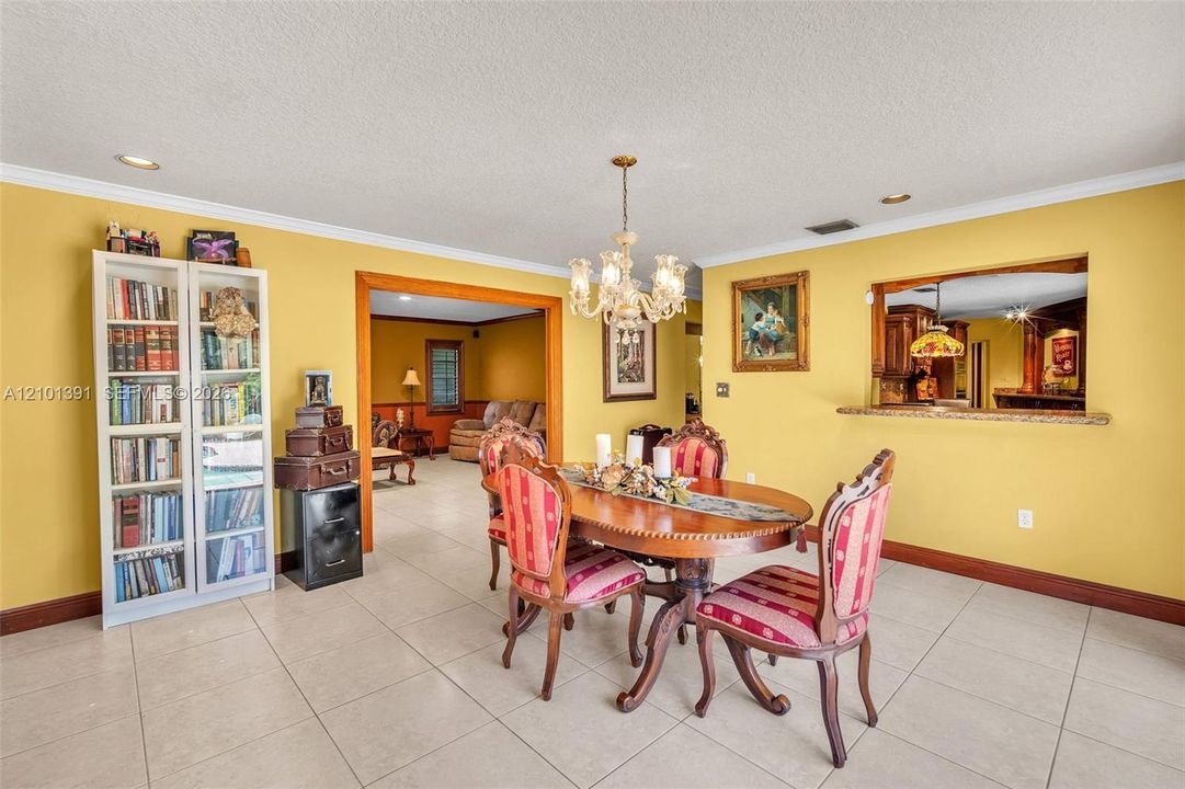 Dining area featuring tile flooring, a decorative chandelier, and a pass-through window with a stone counter