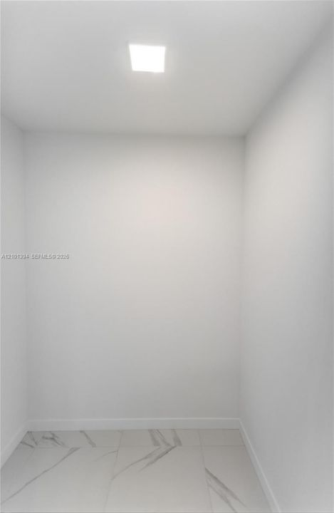 Enclosed space featuring large-format porcelain tile flooring with grey veining and a recessed square ceiling light fixture