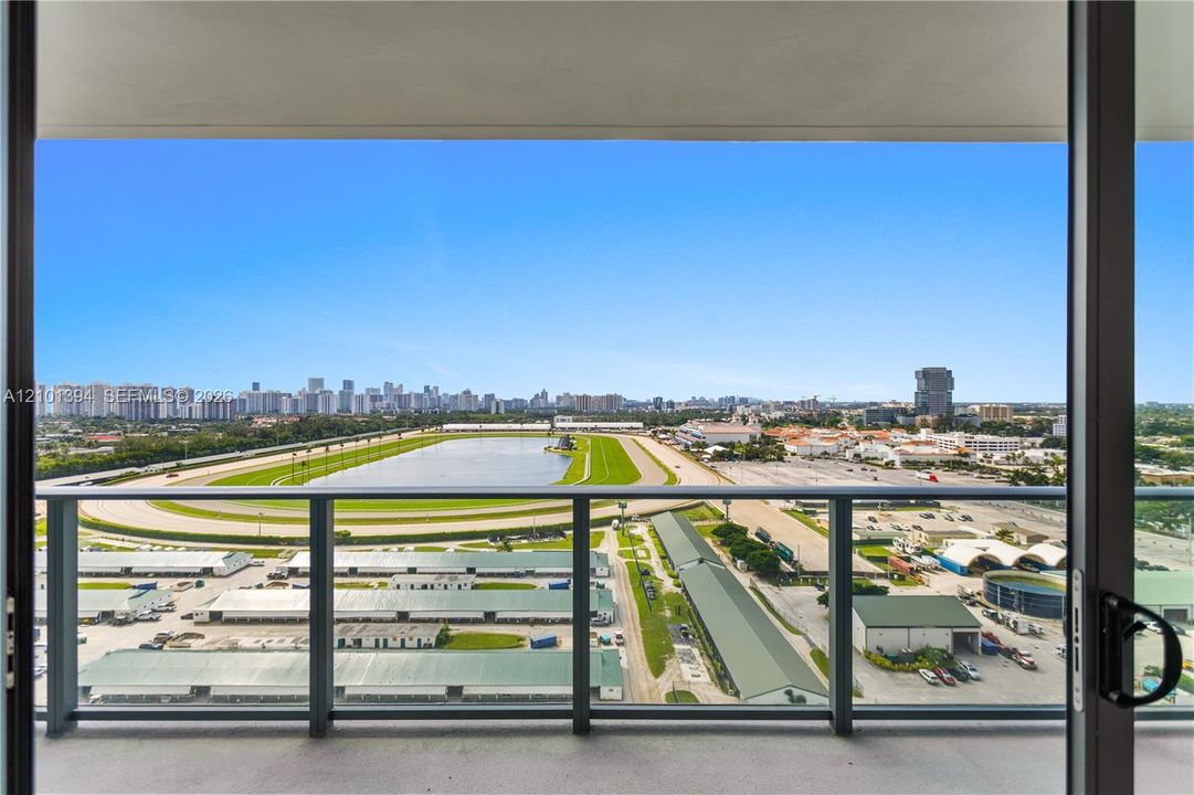 Covered balcony featuring metal railings, concrete flooring, and sliding glass door entry