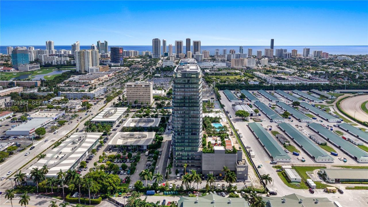 High-rise residential tower featuring glass-facade architecture, podium-level recreational amenities, perimeter landscaping, and a central urban location