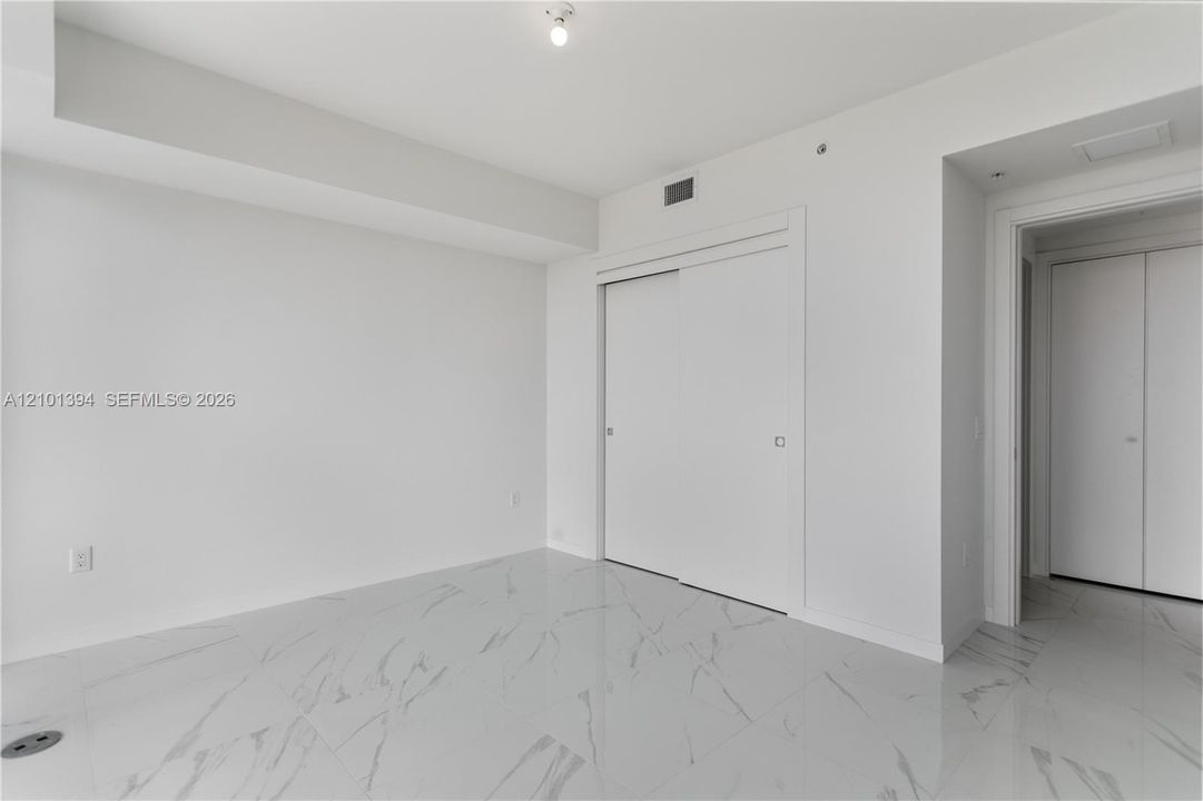 Interior space featuring large-format tile flooring with a neutral veined pattern, floor-to-ceiling sliding closet doors, and recessed ceiling lighting