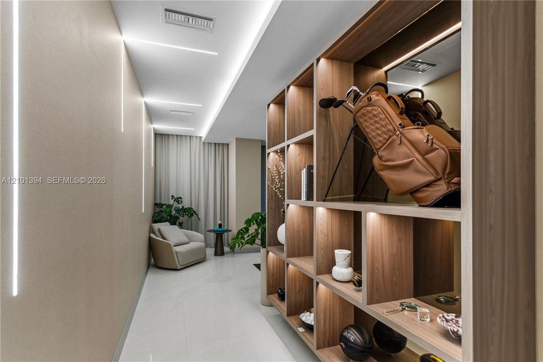 Custom floor-to-ceiling wooden shelving unit with integrated lighting, recessed linear wall lighting, and neutral large-format tile flooring