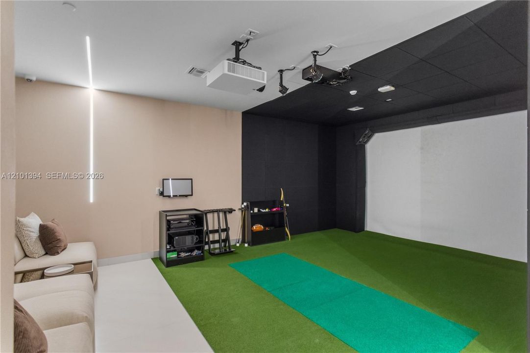 Dedicated recreation room featuring a large-format projection screen, ceiling-mounted projector, custom acoustic ceiling paneling, and integrated vertical LED wall lighting