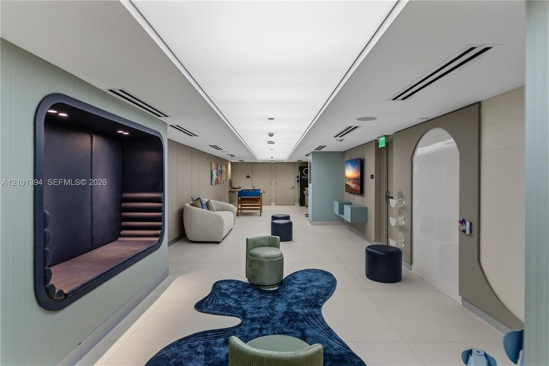 Large format tile flooring, recessed LED ceiling lighting, and built-in alcove seating with dark paneling