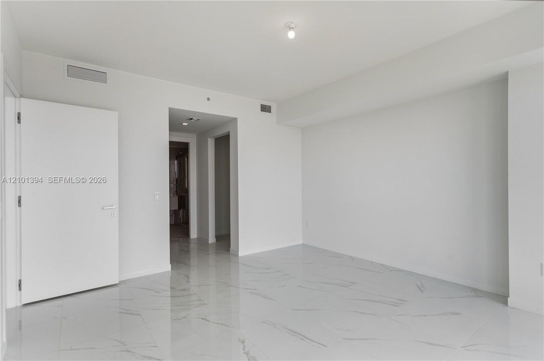 Polished white stone-finish flooring with neutral veining, high ceilings, and neutral wall tones